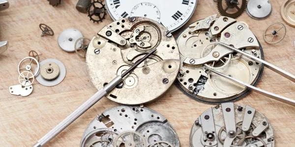 Múltiples movimientos y engranajes de reloj sobre mesa de trabajo