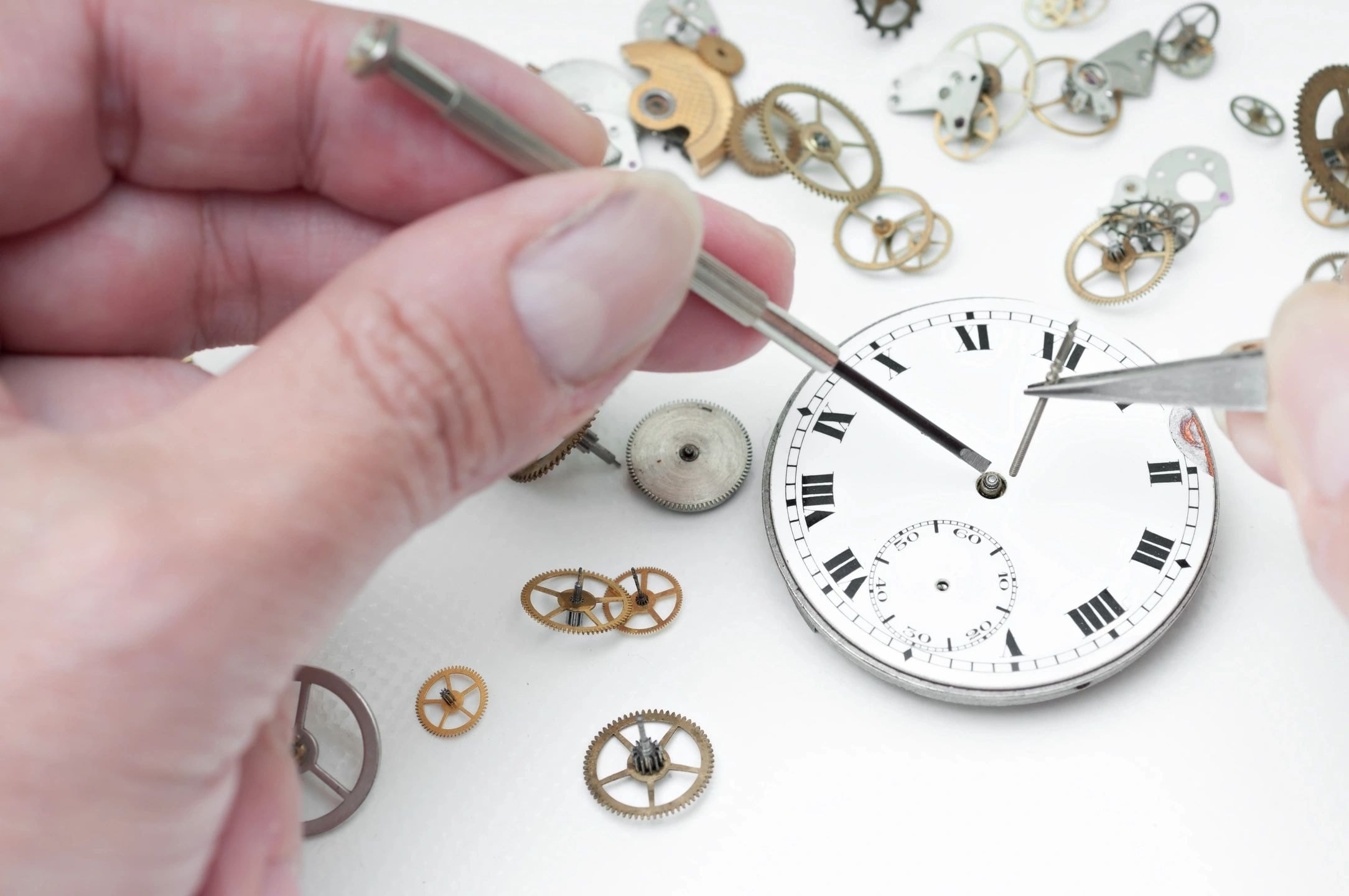 Relojero ensamblando un reloj de bolsillo vintage con herramientas de precisión